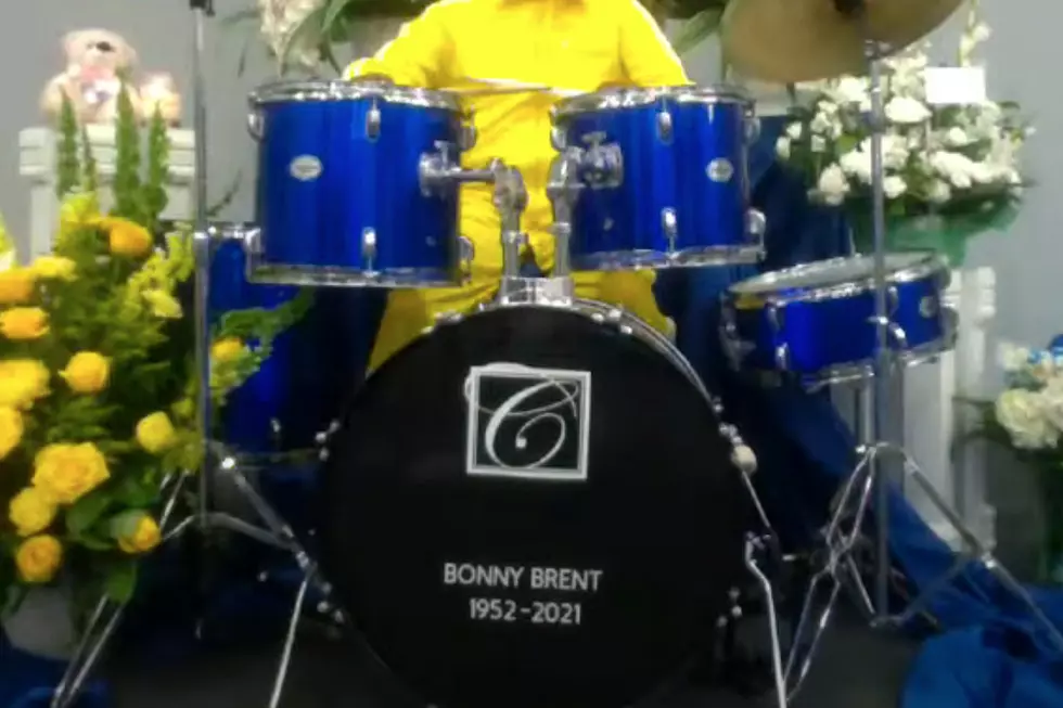 Deceased Drummer Sits Behind a Drum Kit at His Own Funeral