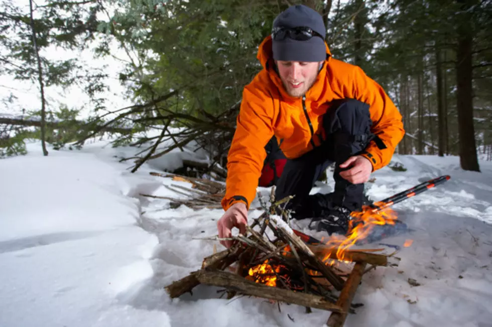 Man kneeling by fire in snow in wilderness