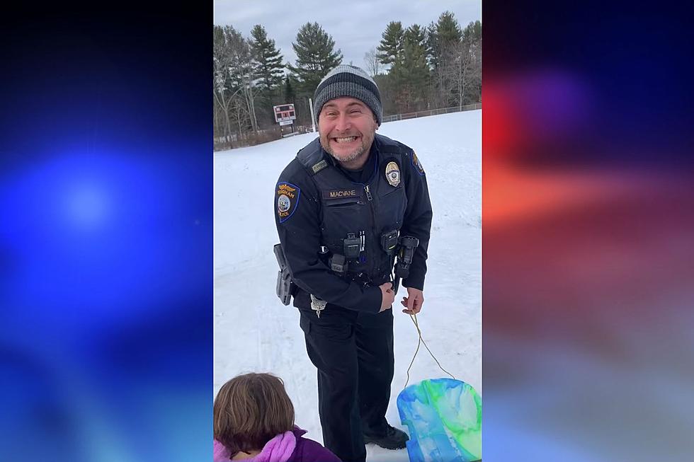 Windham Police Officer Smiles as He Slides Down a Hill with Kids