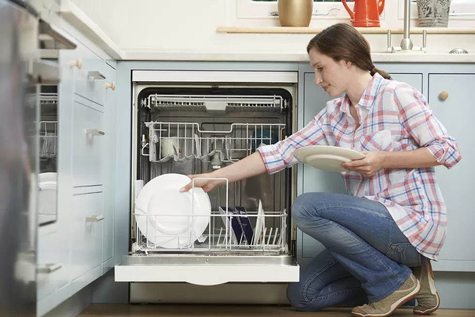 Woman Loading Dishwasher In Kitchen