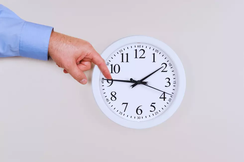 A hand pushes the minute hand back on a clock