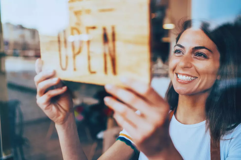 A woman flips a sign to say open in her store