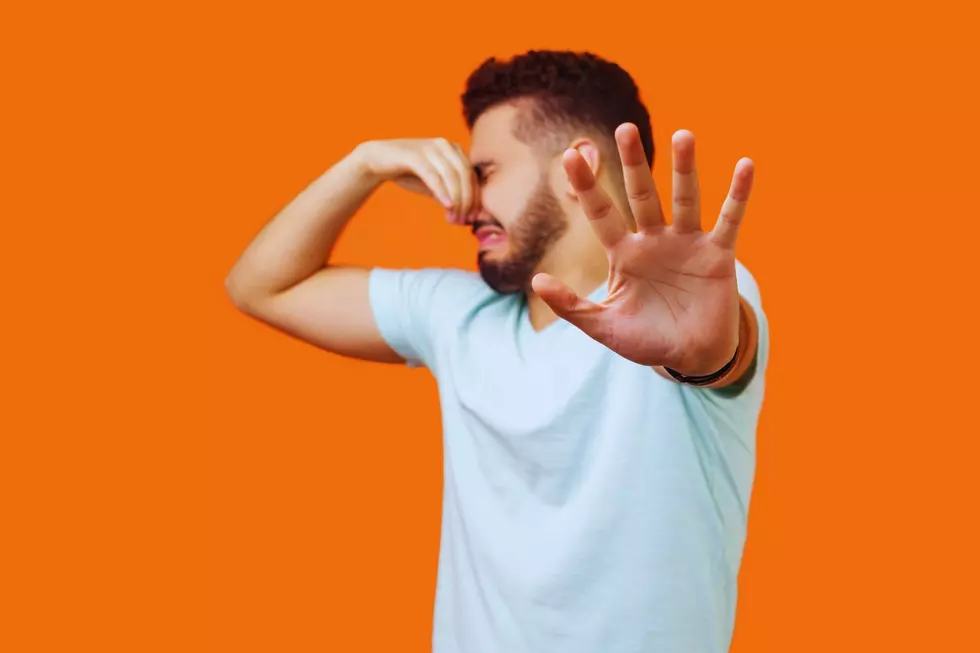 A man holding his nose and putting his hand up as if to say, get away that stinks