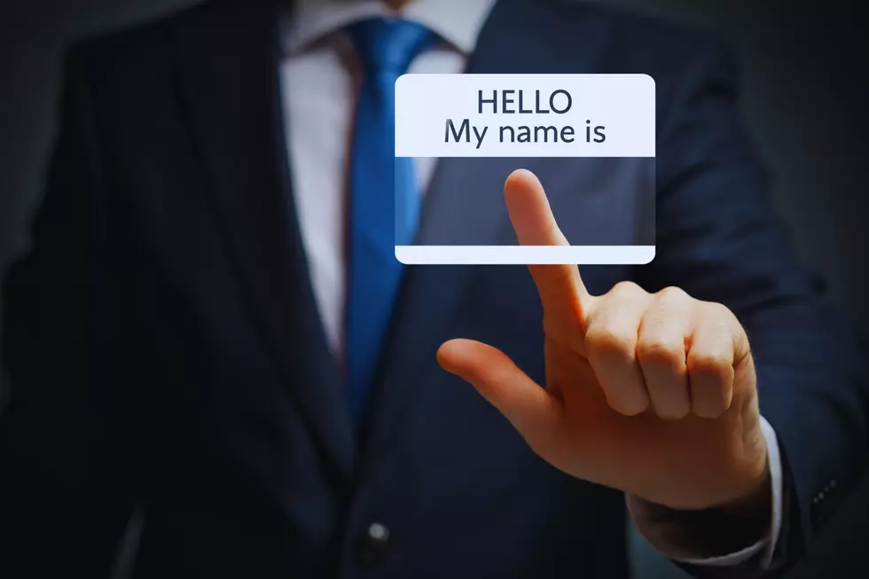 A man in a suit touching a "hello my name is" card