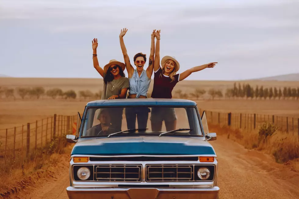 3 girls standing up in the bed of pickup truck