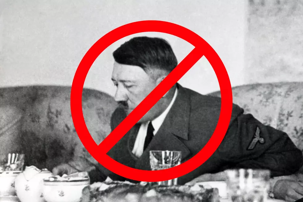 Hitler eating at a table with a red slash circle over his face