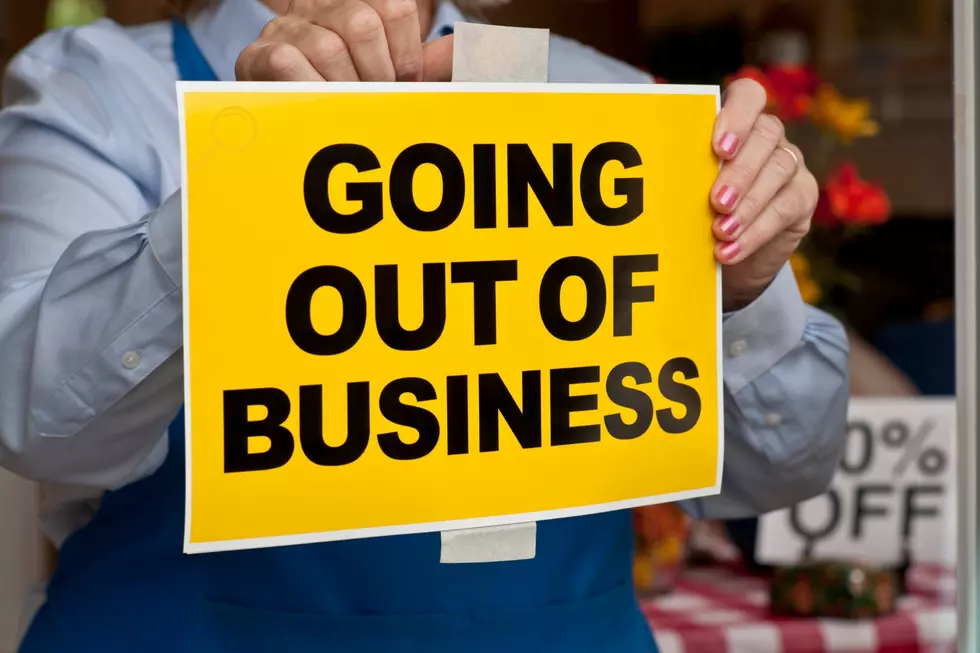 A woman hangs a yellow sign with black lettering that says "going out of business"