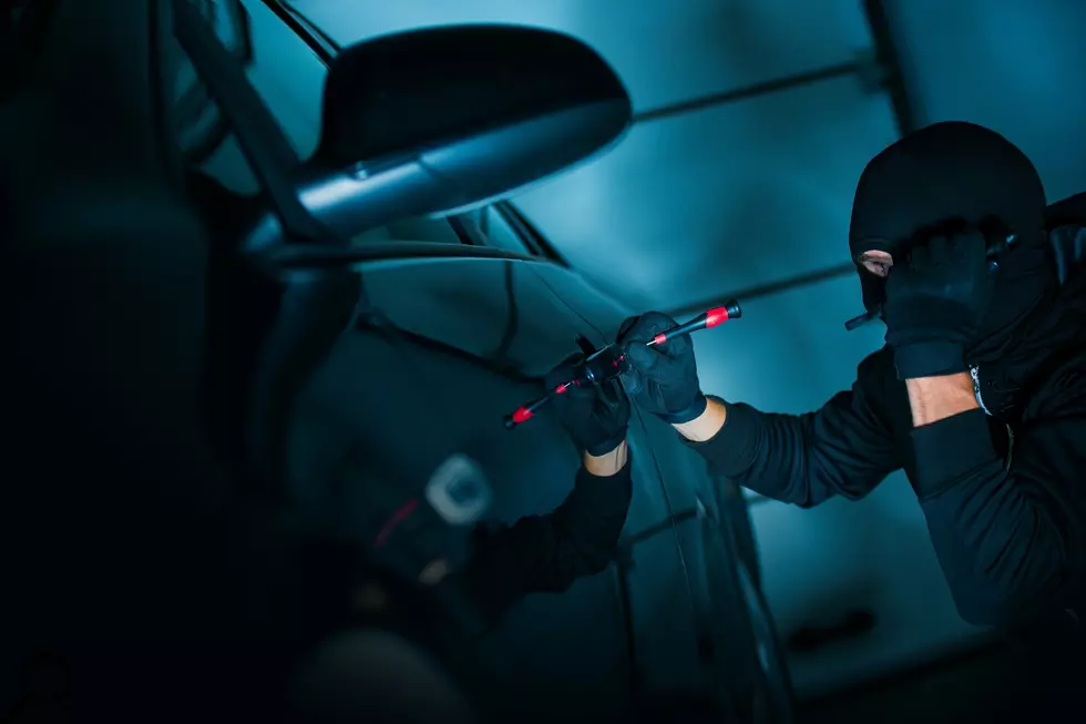 A car thief breaks into a car at night