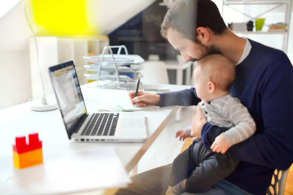 A father works from home with a baby on his lap