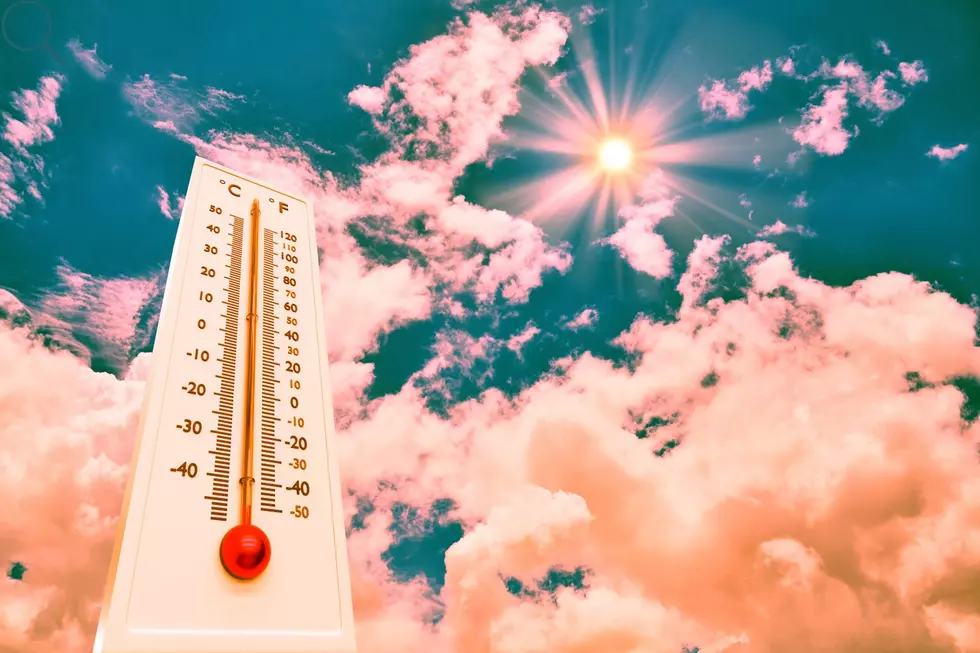 Thermometer showing temps in the 100s in front of pink clouds and a bright sun representing a hot summer day