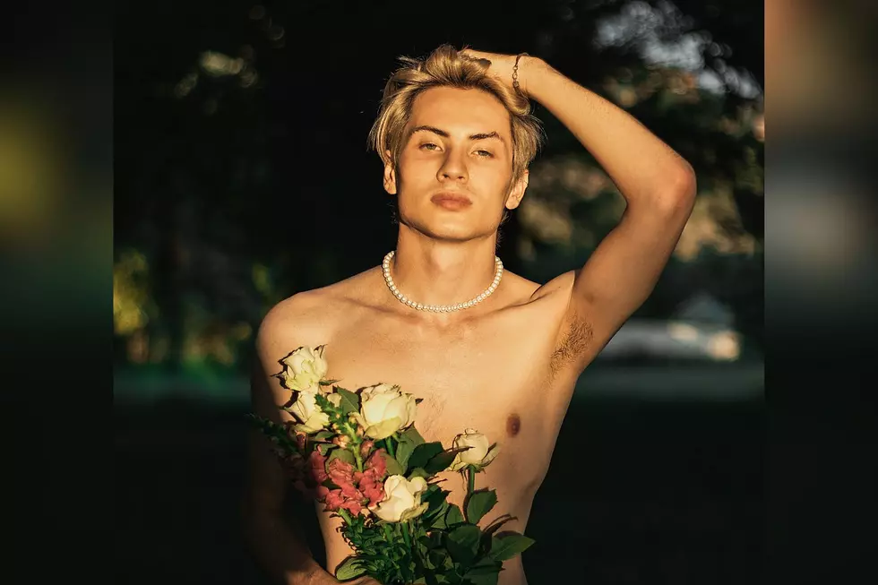 A nude man holding a bunch of flowers