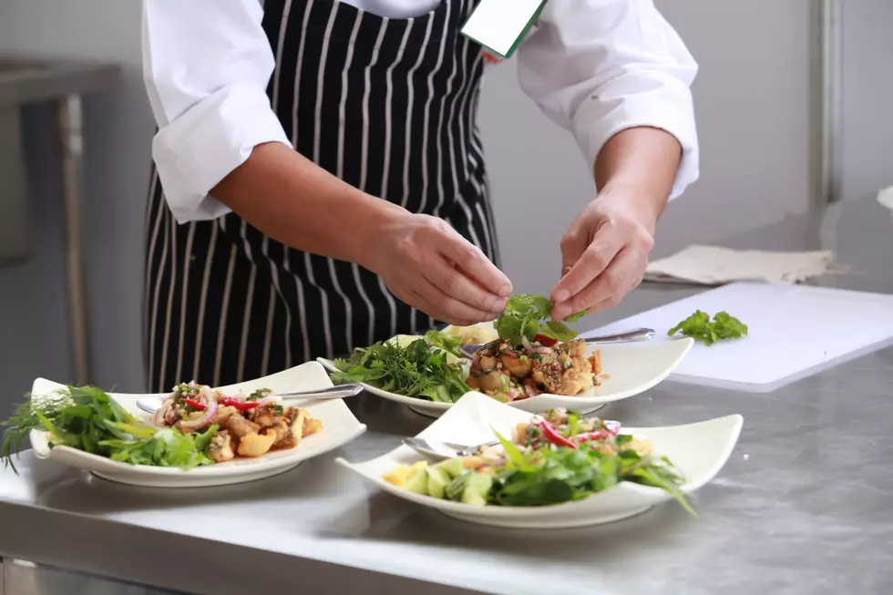 A chef places the finishing touches on 3 plates to be served