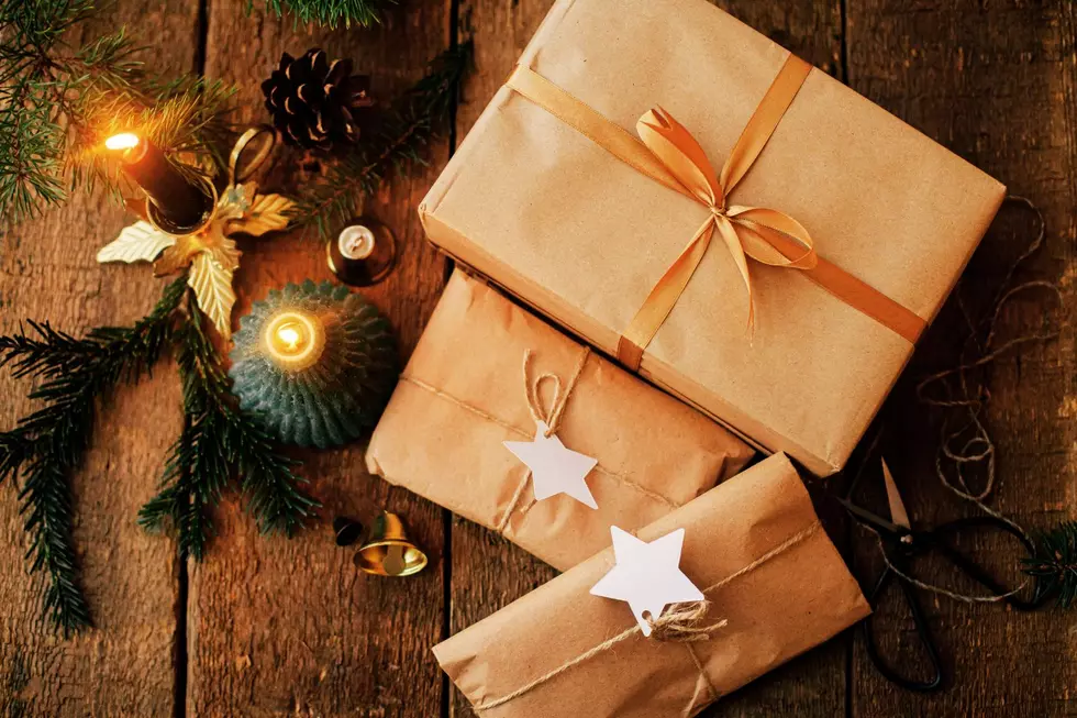 Presents wrapped in packing paper on a wooden table with a candle