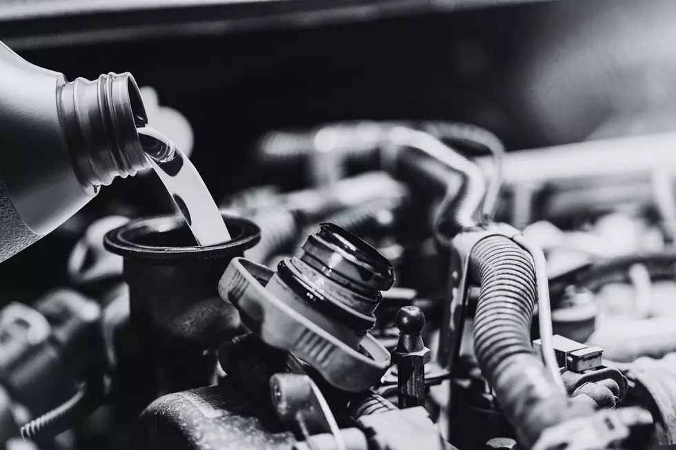 an engine with the oil cap off and someone pouring in oil