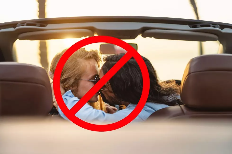Two people kissing in a car with a "no" sign over them