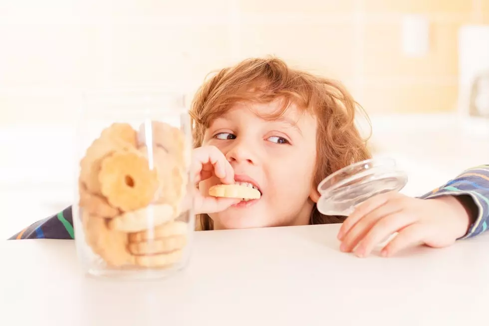A young boy sneaks a cookie out of the jar