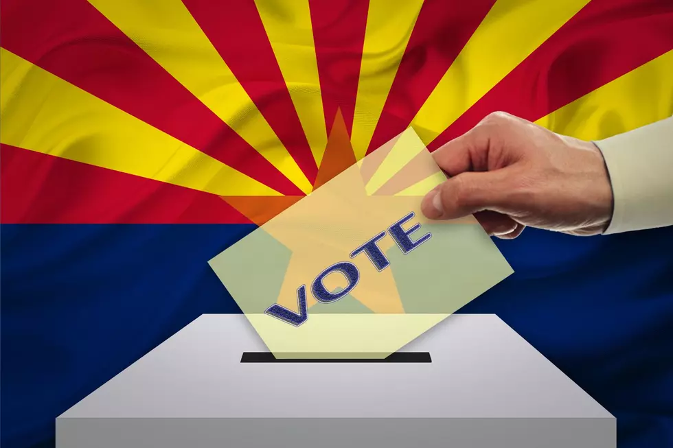 A hand casting a ballot in front of an Arizona flag