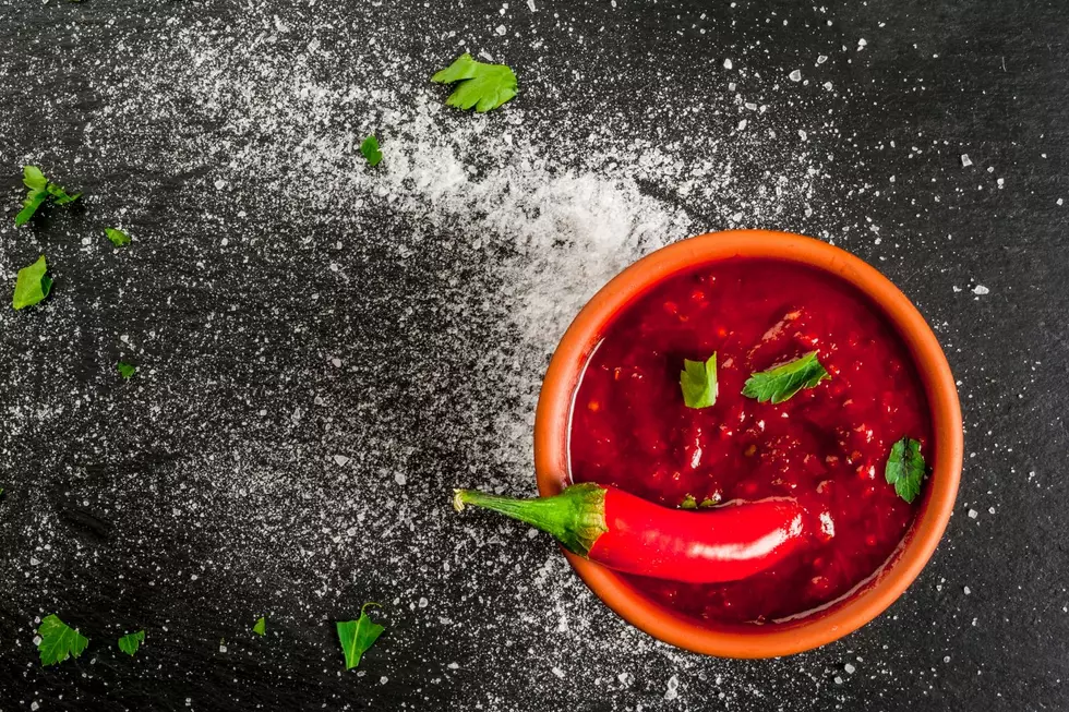 A chili pepper sits in a bowl of hot sauce