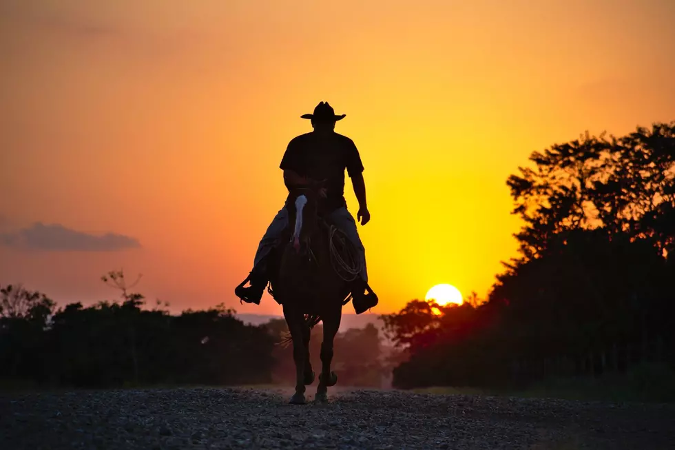A cowboy rides off away from the sunset