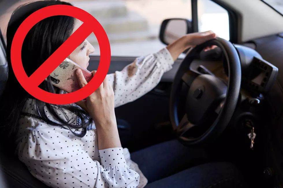 A woman uses her phone while driving with a big red cross out over her