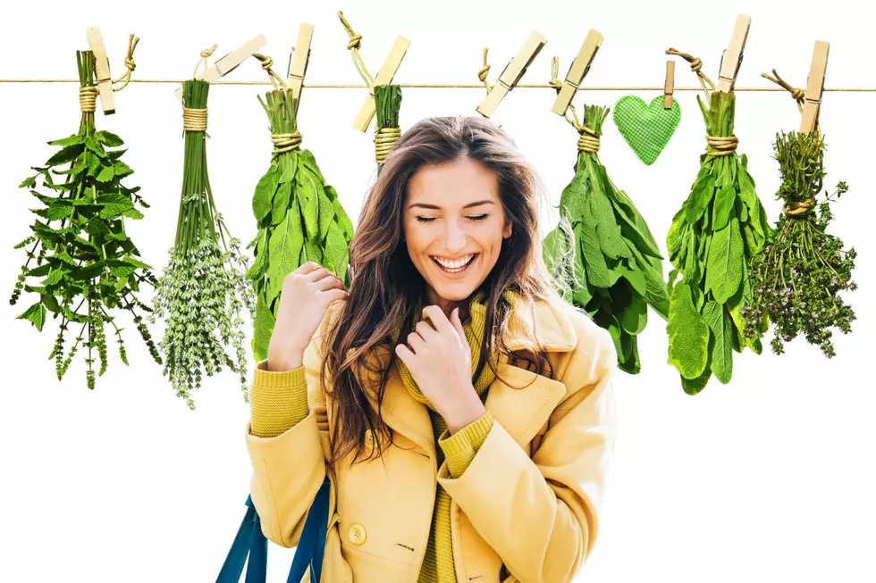 Woman smiles with hanging herbs behind her.