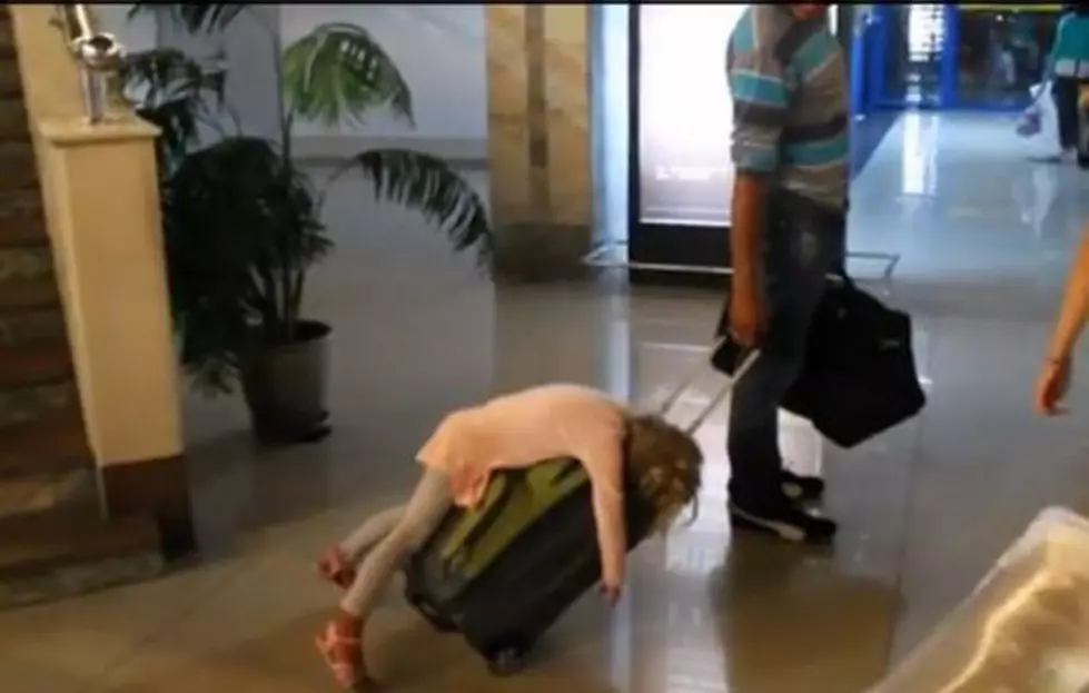 Hilarious Video Shows Exhausted Kid Being Rolled Through an Airport on Top Of a Suitcase