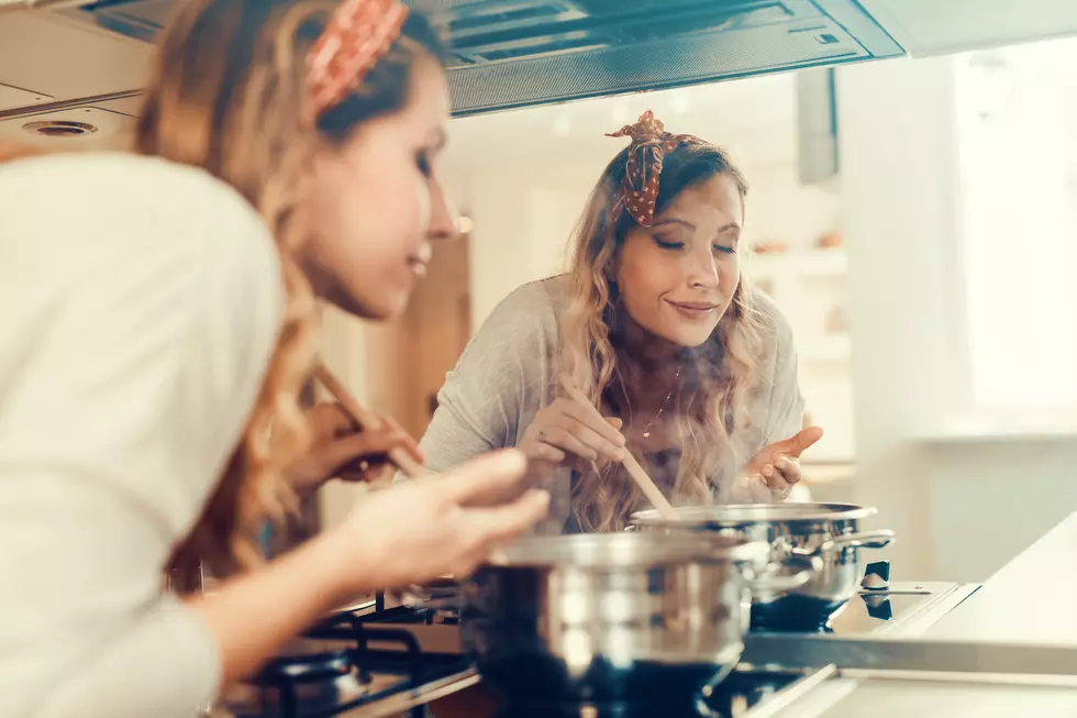 Young women cooking and testing the food in the kitchen.