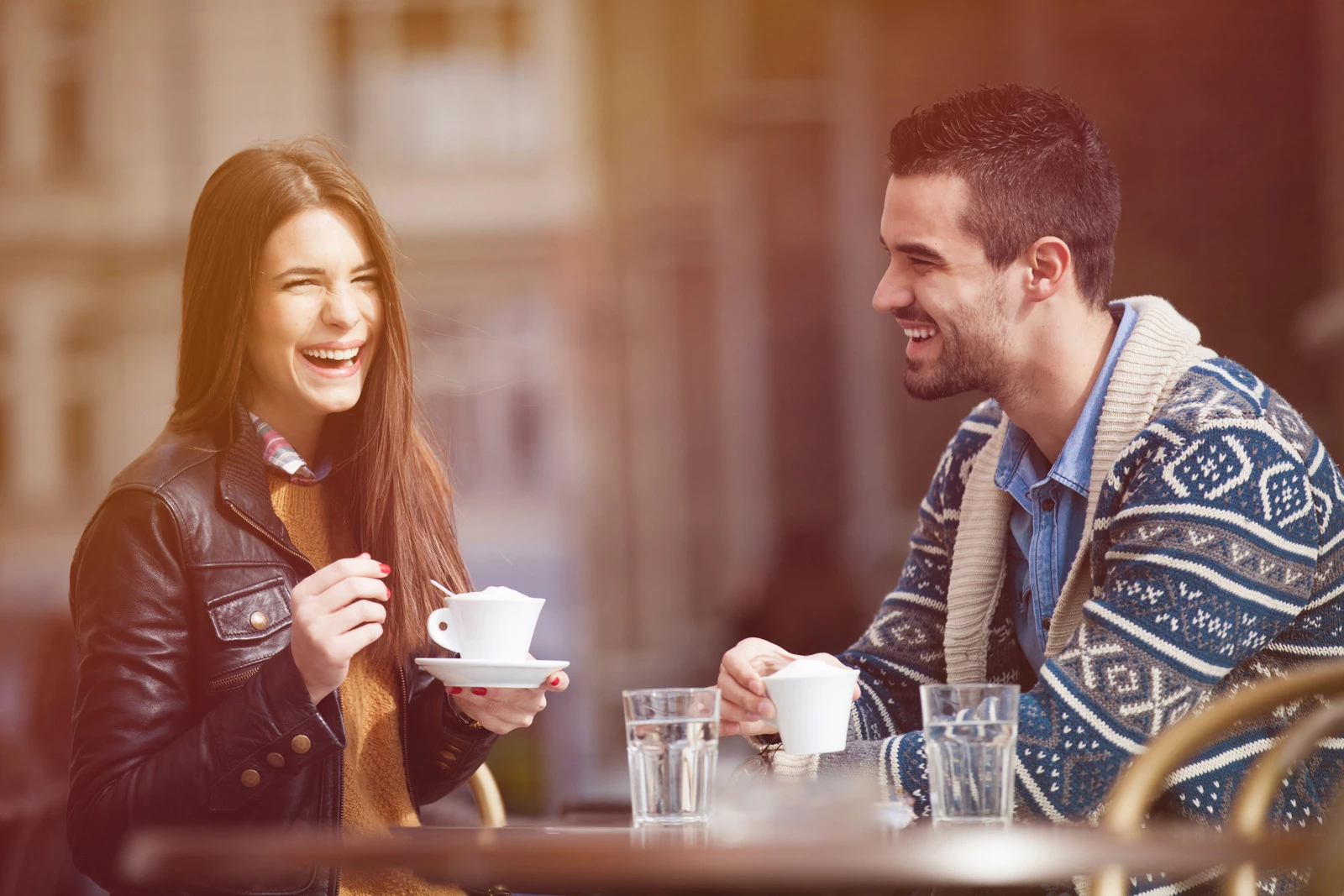 Happy young couple sitting in a cafe outside on a beautiful autumn day.