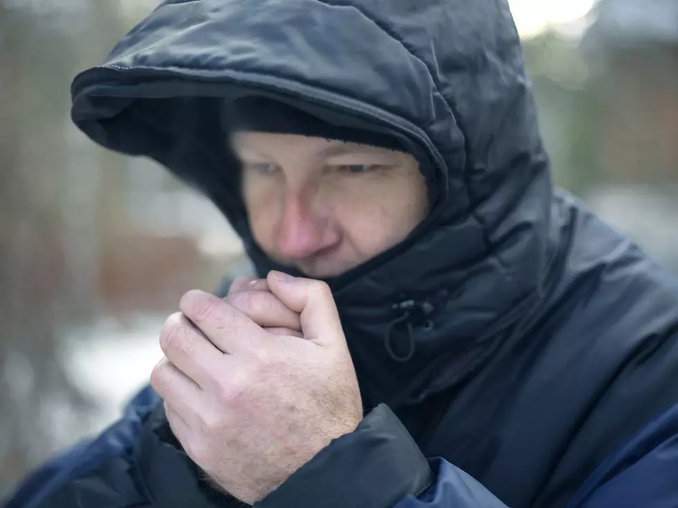 Man wearing hood warming his hands, outdoor horizontal shot