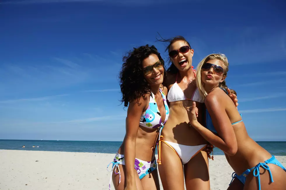 Three young women smiling on beach, portrait, close-up