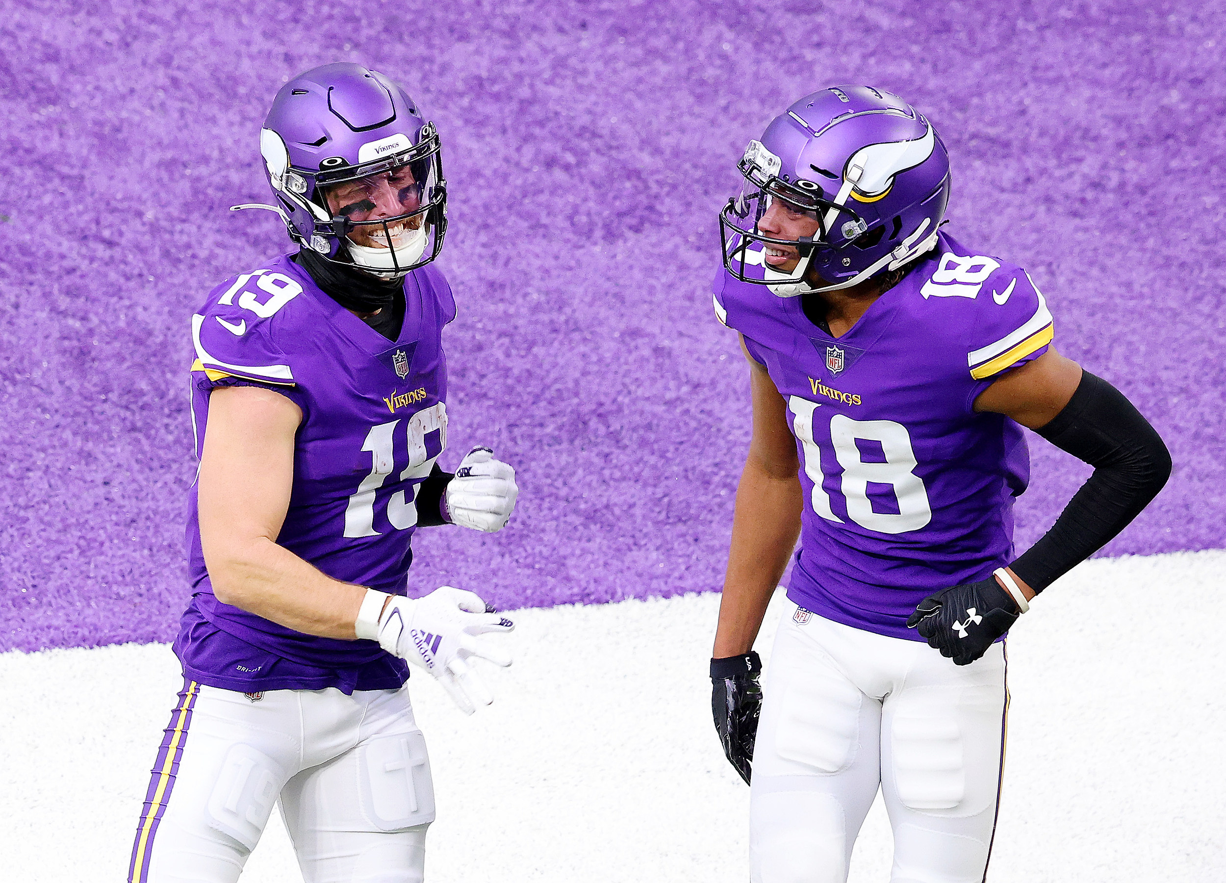 Minnesota Vikings wide receiver Justin Jefferson (18) is seen from the back  during pregame warmups with the American flag, Vikings 60 years logo, NFL  cancer awareness logo and the It Takes All