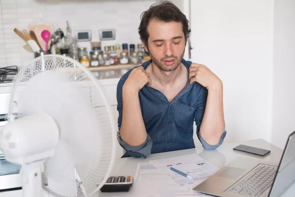 Sweaty man trying to refresh from heat with a fan