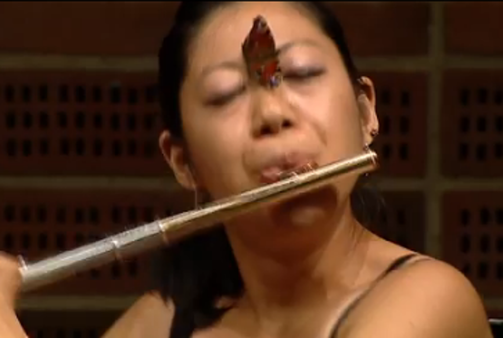 Woman Playing the Flute Doesn’t Flinch When a Butterfly Lands on her Face