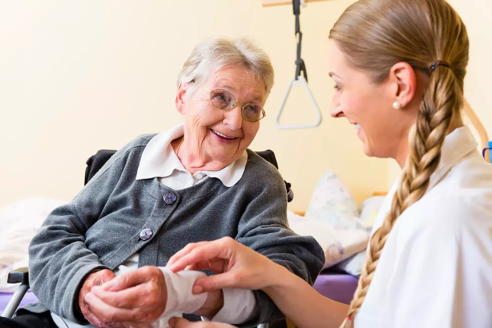 Nurse taking care of senior woman in retirement home bandaging a wound