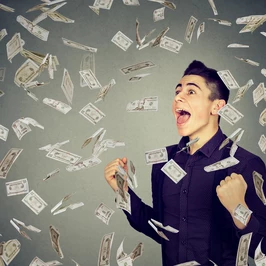 Man celebrates success under money rain falling down dollar banknotes