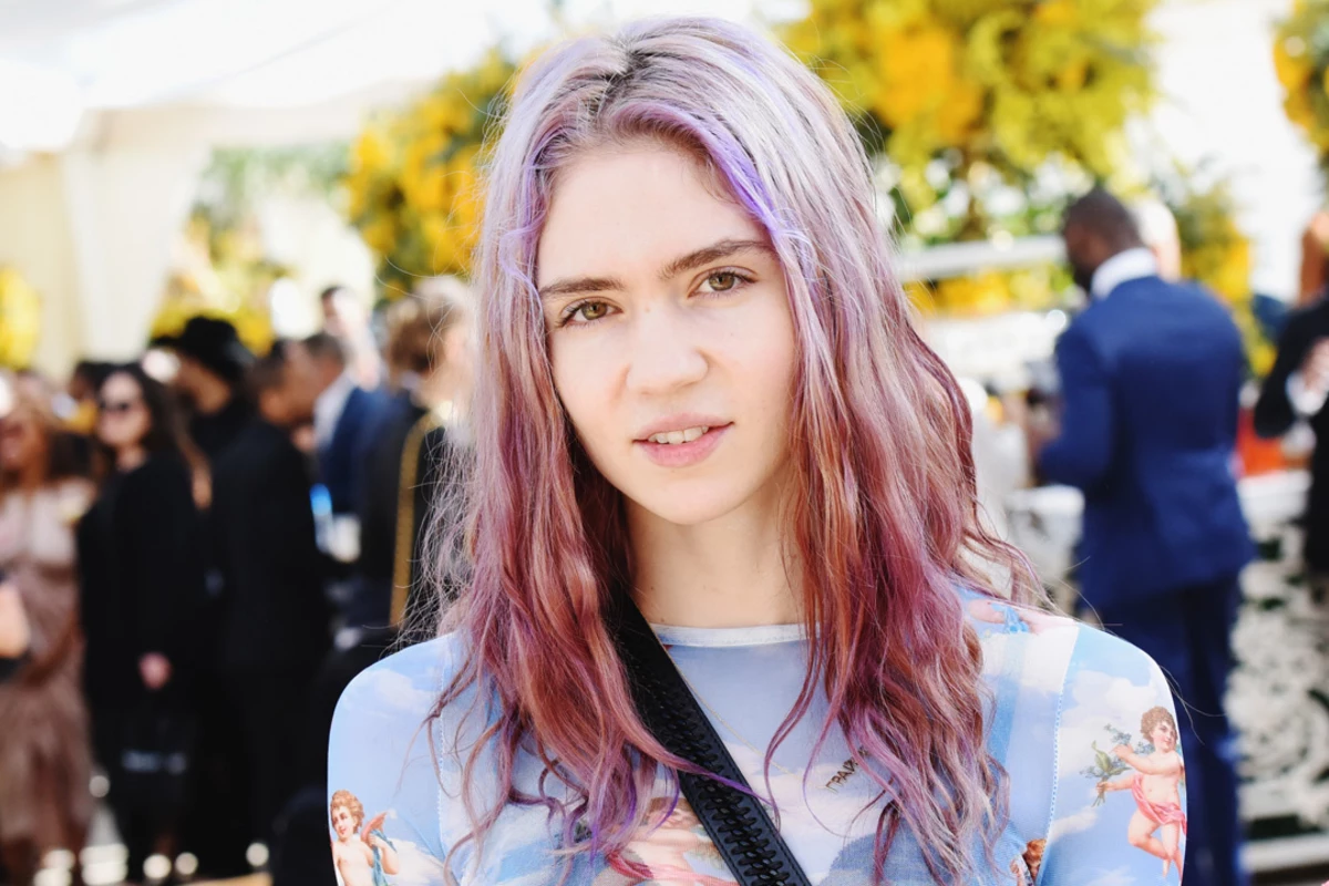 Grimes Trolls Paparazzi By Reading Karl Marx in Costume