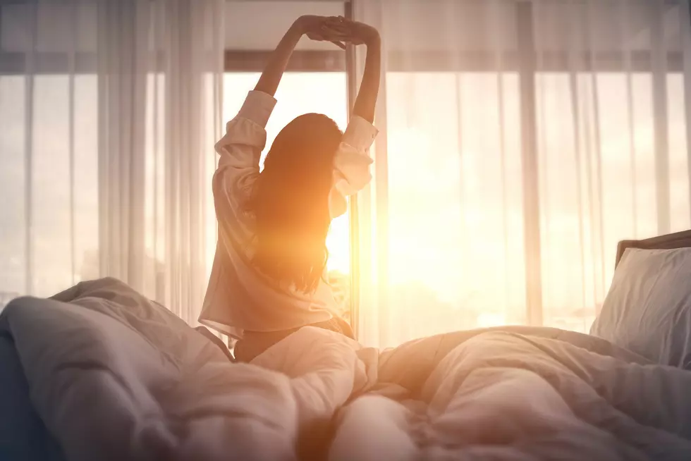 Happy woman stretching in bed after waking up.