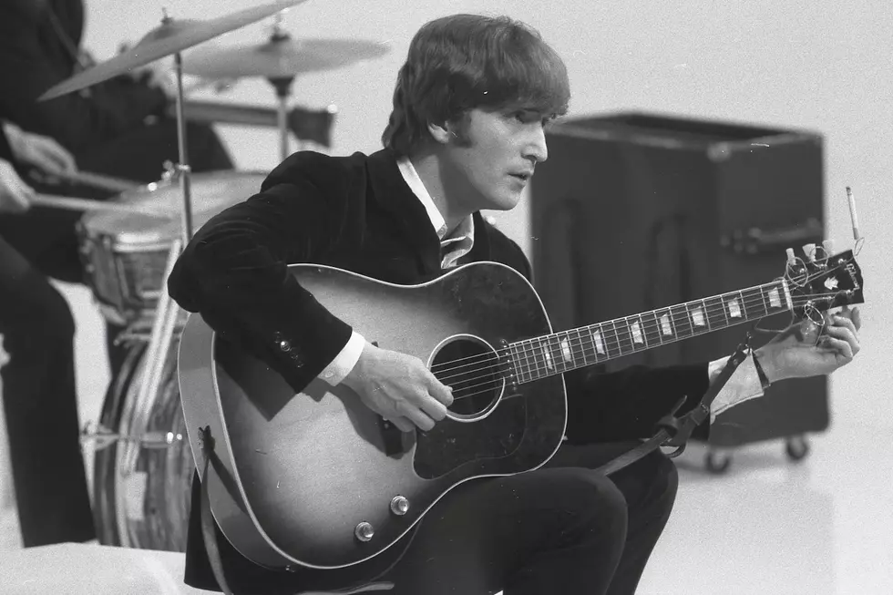 John Lennon tunes an acoustic guitar for an early-era Beatles performance. (Max Scheler / Redferns, Getty Images)
