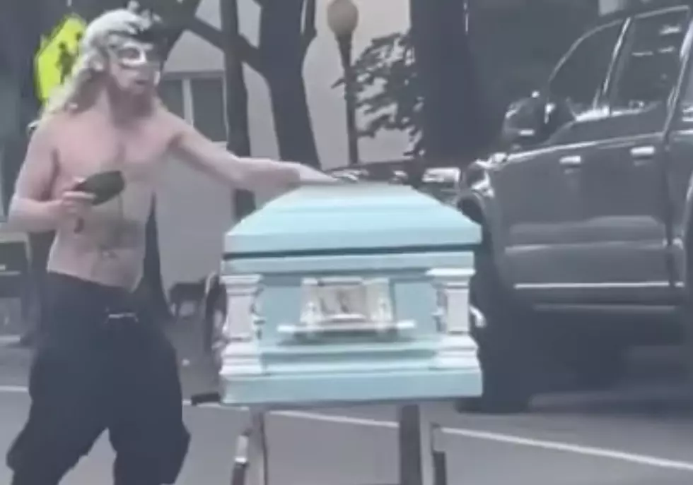 Man Wearing Mardi Gras Mask Pushes Casket Down Roadway [VIDEO]