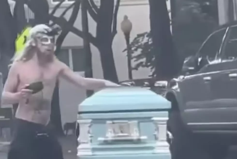 Man Wearing Mardi Gras Mask Pushes Casket Down Roadway [VIDEO]