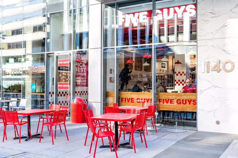 Five Guys restaurant, store burger chain entrance in District of Columbia with chairs, tables, outside, outdoor sitting area, people inside eating