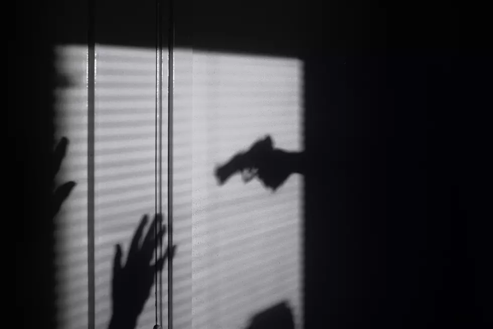 Gun and Raised Hands in Shadow