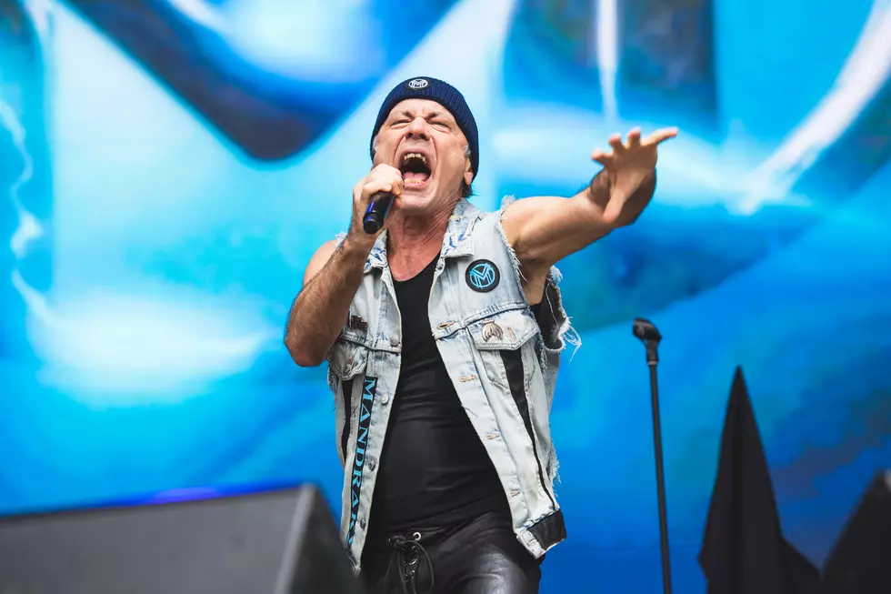 iron maiden singer bruce dickinson performing solo with arm outstretched and beanie on head