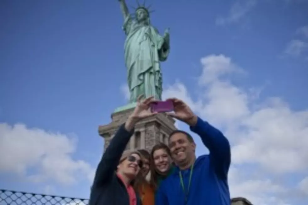 Tourists pose for pictures during a visit to the Statue of Liberty after it was reopened on Sunday