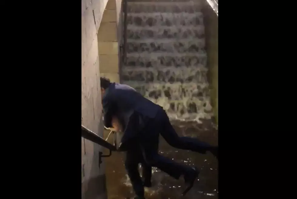 Woman carries man on her back through flooded train station