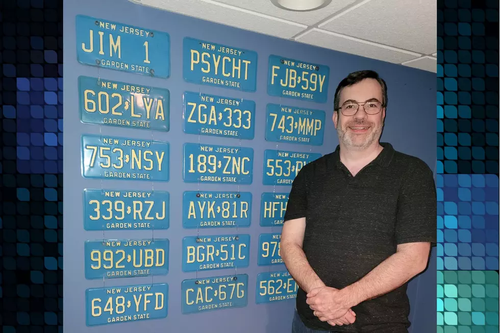 Jim Moini stands alongside a sample of his New Jersey license plate collection.