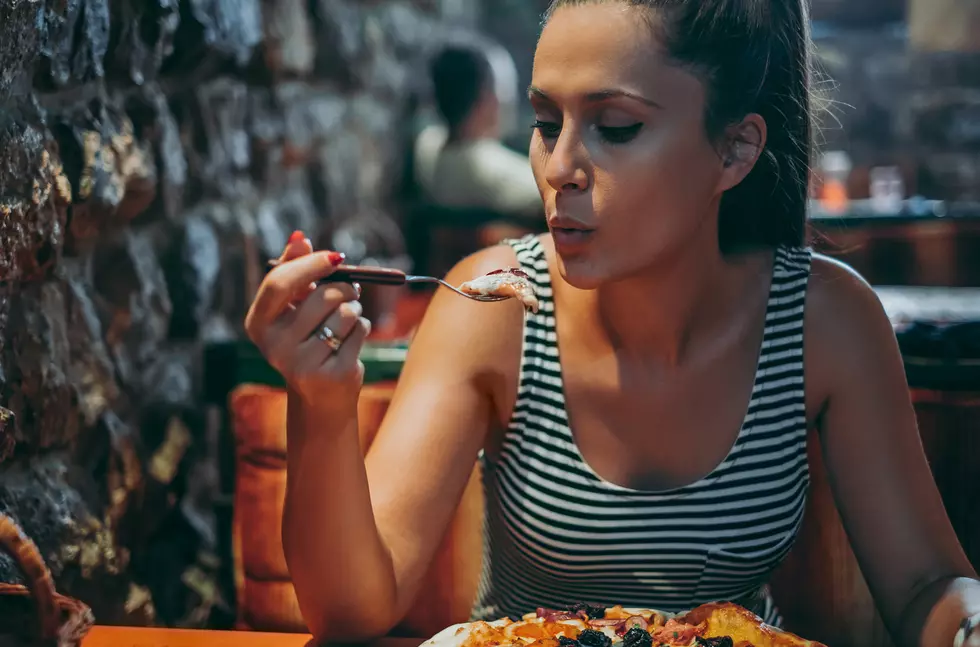 Girl blowing on a hot piece of pizza at the restaurant