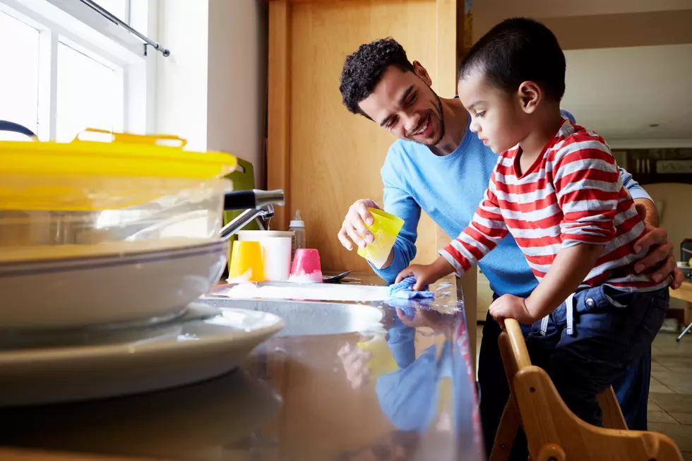 Son Helping Father To Wash Dishes In Kitchen Sink