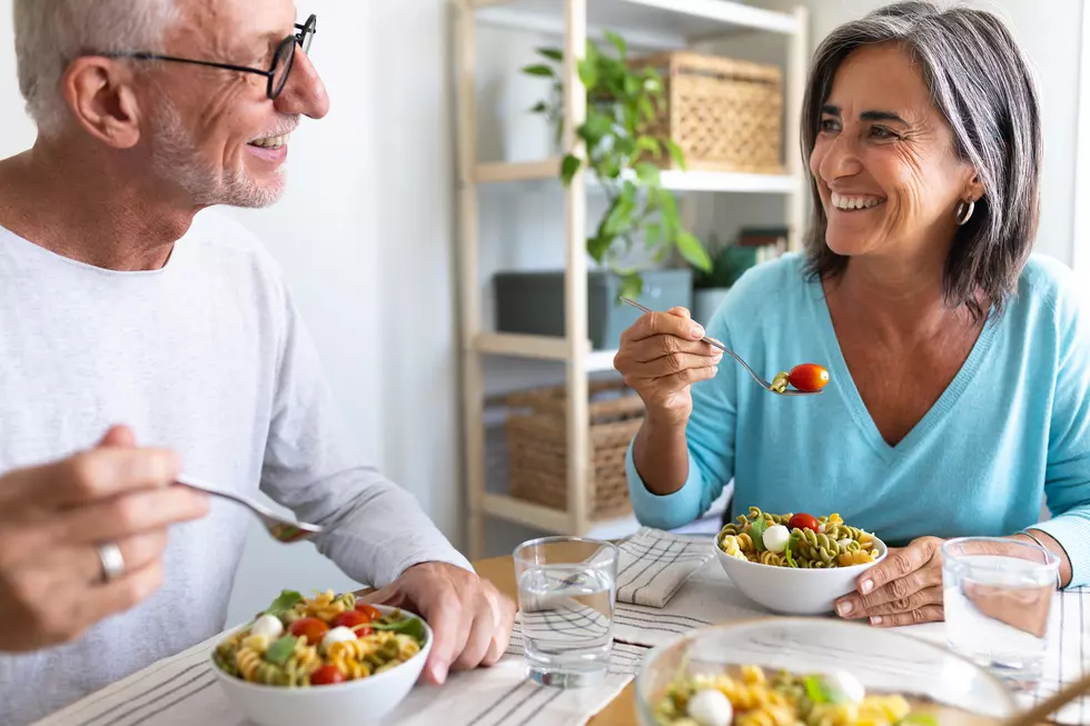 Mature married couple enjoying pasta salad for lunch. Couple looking at each other smiling while eating.