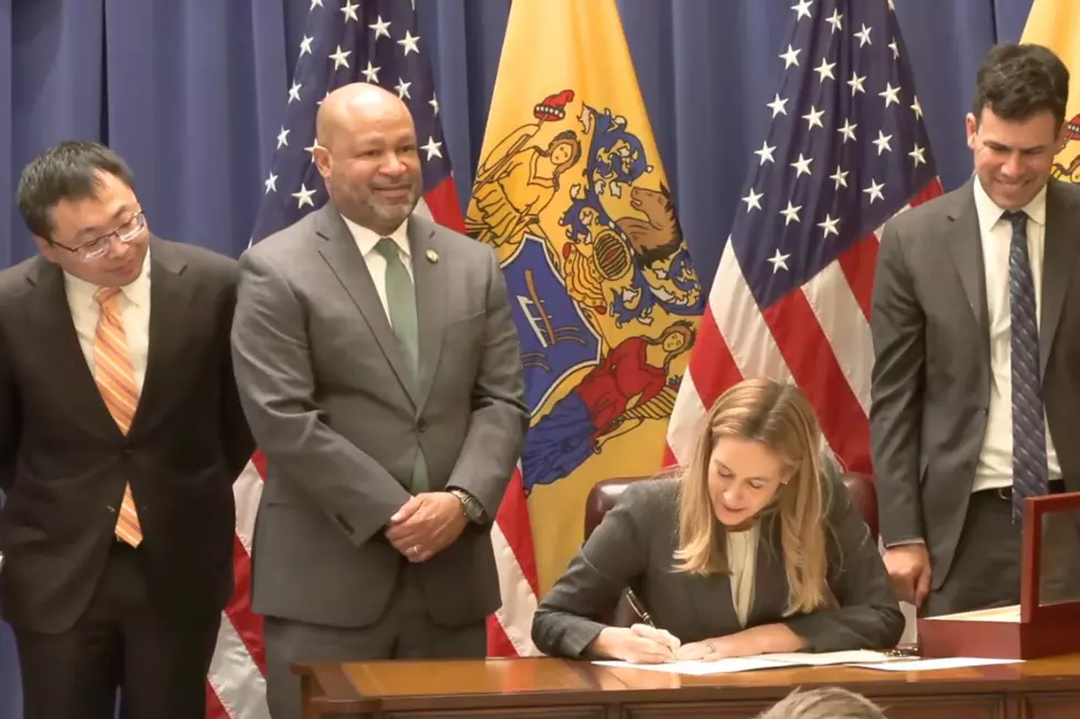 Gov. Mikie Sherrill signs an executive order as NJ Jeopardy! champ Jamie Ding and Senator Benjie Wimberly look on (Gov. Mikie Sherrill via Youtube)